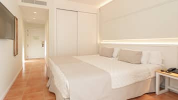 Une chambre à coucher avec un lit, une table de chevet et un téléviseur fixé au mur.