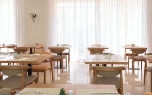 A modern dining area with multiple tables and chairs, large windows with sheer curtains, and a clean, polished floor. - Hotel Bordoy Don Antonio (Calvia)