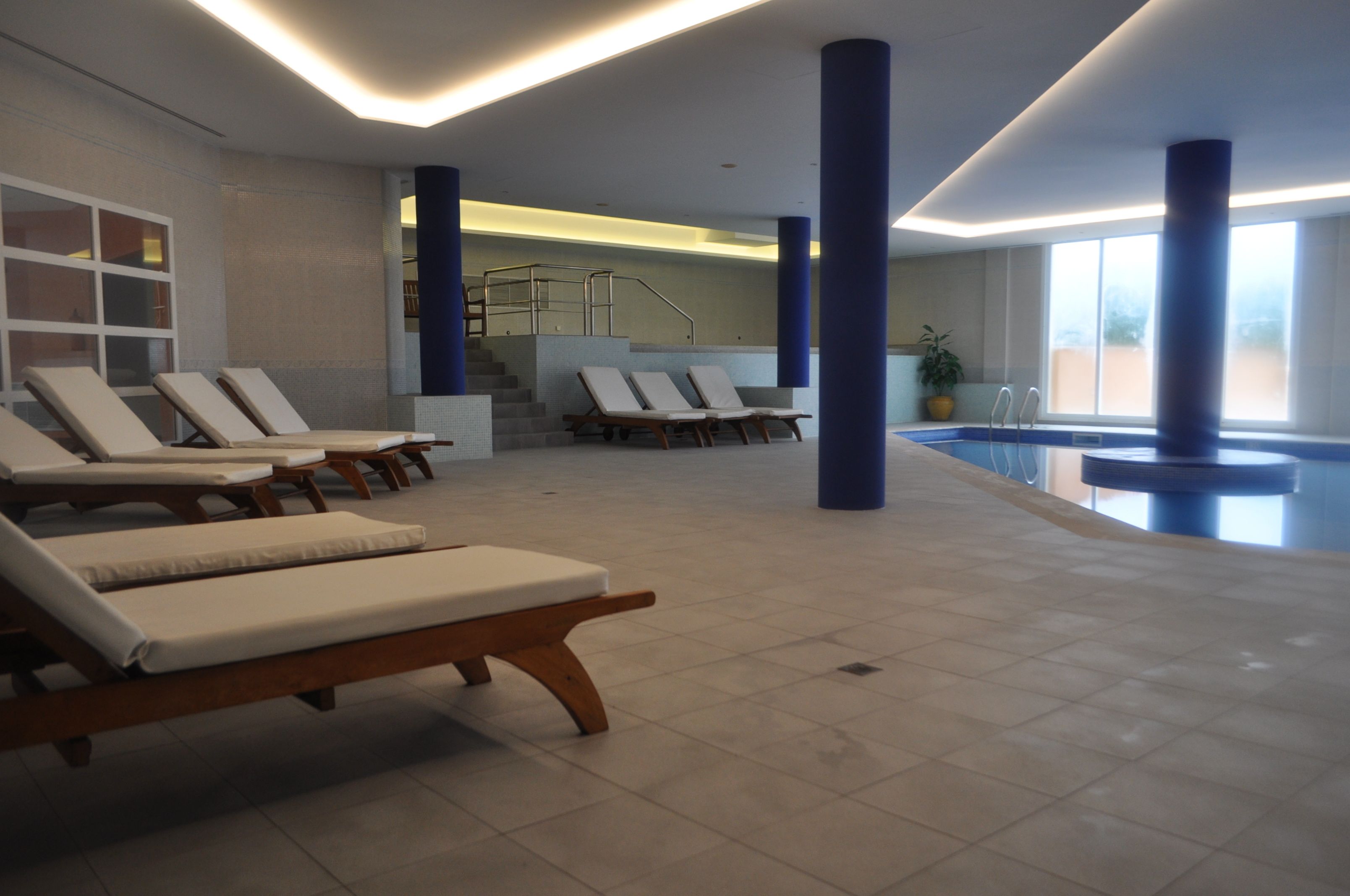 A swimming pool area with lounge chairs, a staircase, and a potted plant.
