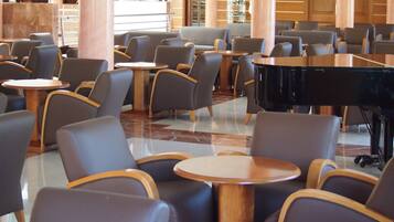 Un'ampia hall con diverse zone relax, un pianoforte a coda e un pavimento in marmo.