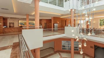 Un hall d’entrée spacieux, doté d’un sol en marbre, d’un comptoir de réception et d’une balustrade en verre donnant sur le niveau inférieur.