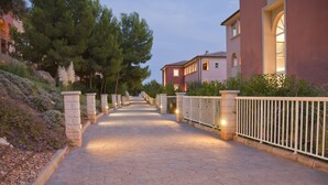 A paved pathway flanked by stone pillars and a white metal fence, leading to a building with a red facade and arched windows. - Hotel Bordoy Don Antonio (Calvia)