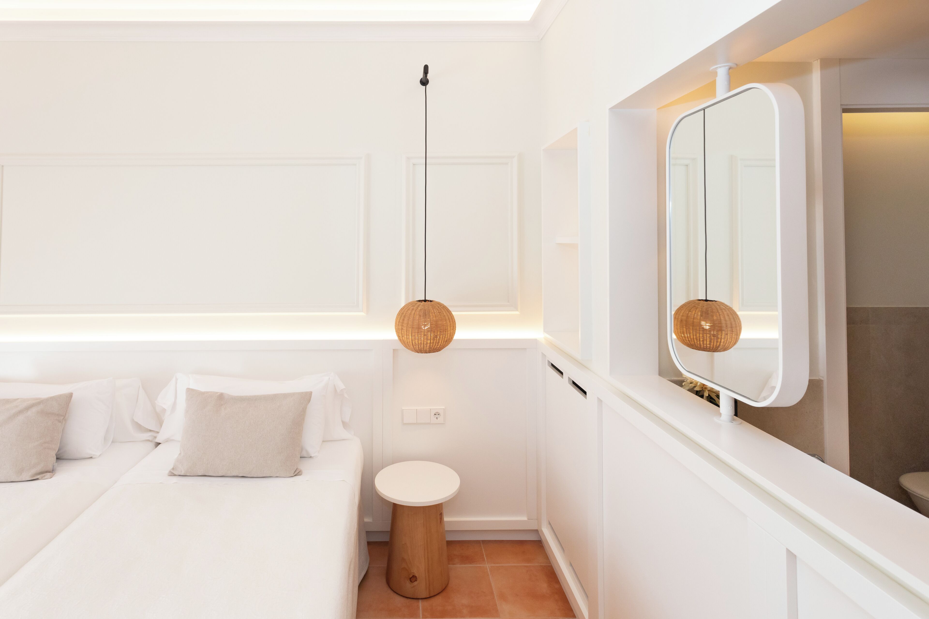 Quarto moderno com cama, mesa de cabeceira e espelho.