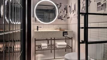 Un baño moderno con un espejo redondo, un lavabo con toallero y un inodoro.