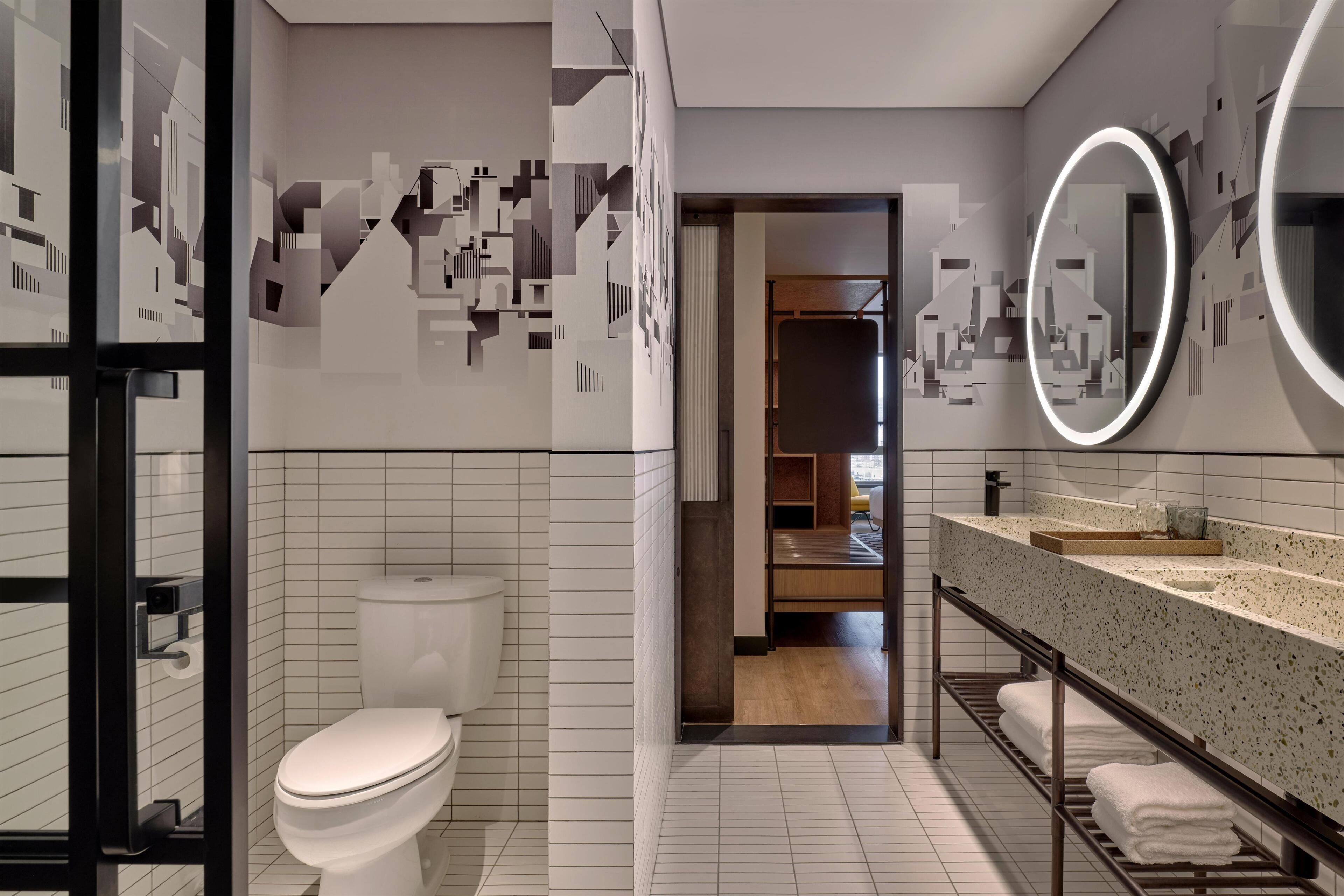 A modern bathroom with a toilet, a sink with a mirror, and a shower area.