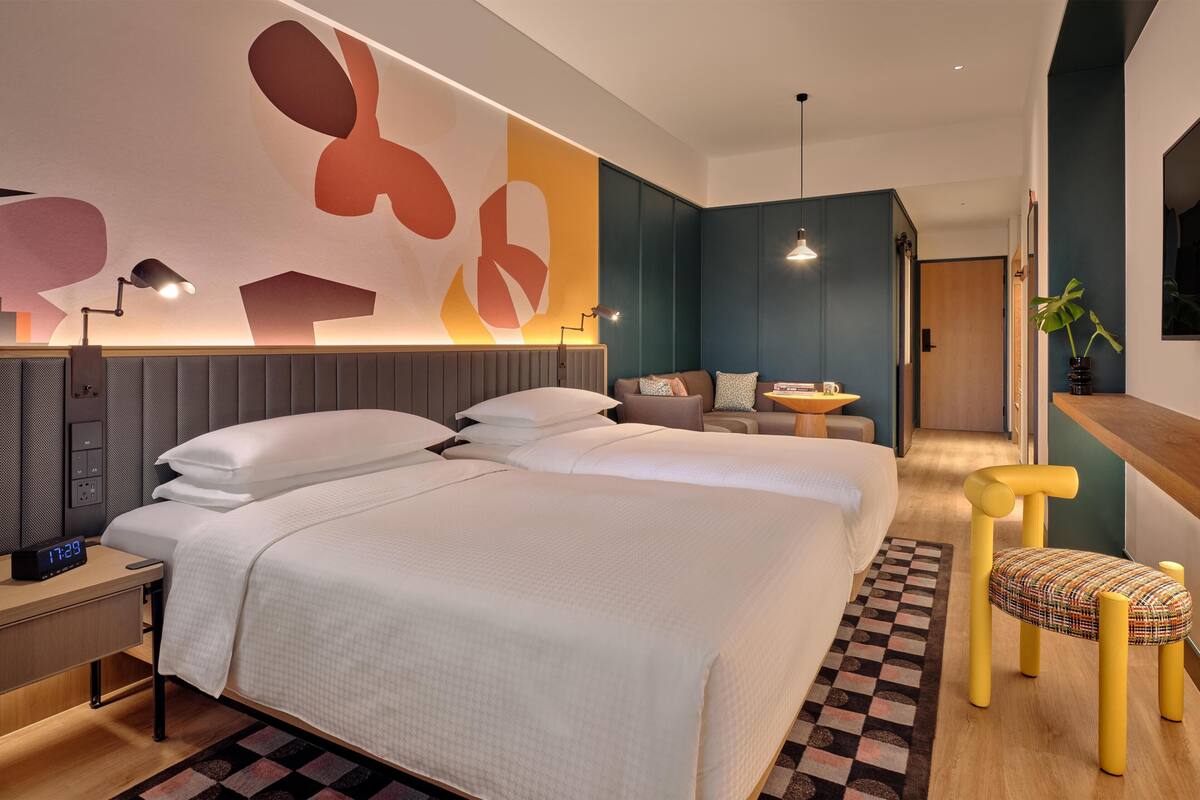 A modern hotel room with a large bed, bedside tables, a desk, and a chair.