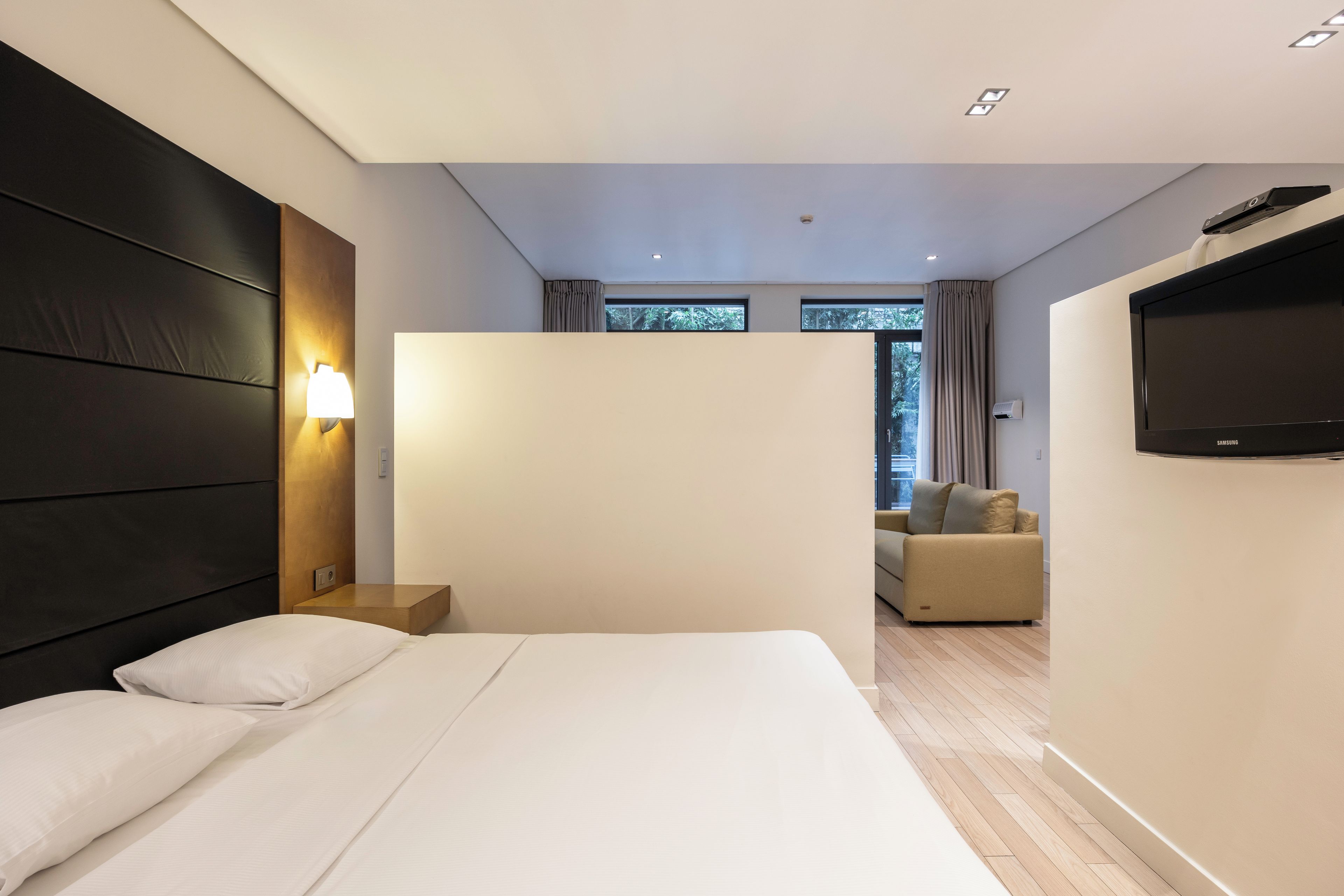 Habitación de hotel moderna con una cama grande, un televisor de pantalla plana en la pared y vistas al exterior a través del ventanal.