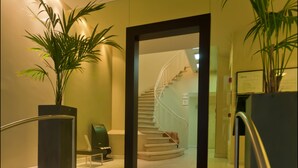 A modern hotel lobby with a marble staircase, a reception desk, and a spiral staircase leading to upper floors. - B-aparthotel Grand Place (Brussels)