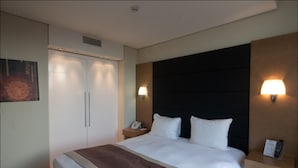 A hotel room with a large bed, bedside lamps, a nightstand, and a wardrobe. - B-aparthotel Grand Place (Brussels)