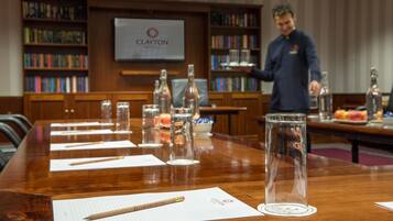 A conference table with lined papers, pens, and glass bottles in a hotel setting.