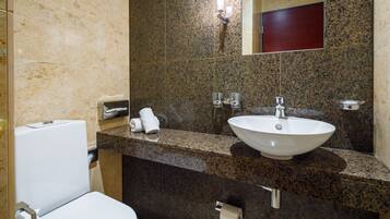 A bathroom with a white toilet, a sink with a mirror above it, and a towel rack with towels.
