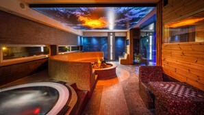 Un spa moderne doté d’un plancher chauffant, d’un jacuzzi et d’un projecteur au plafond diffusant une image de coucher de soleil.