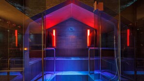 Une pièce moderne aux murs de verre, dotée d’un espace salon central et d’un plafond éclairé en rouge.