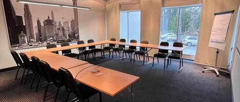 Una sala de conferencias con una larga mesa, sillas, un proyector y una pizarra.