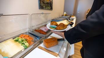 A buffet with various food items including cheese, bread, and pastries.
