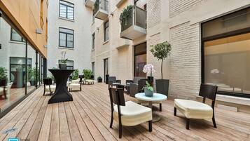 Eine moderne Terrassengrundstueck mit Holzboden, bequemen Sitzgelegenheiten und Topfpflanzen.
