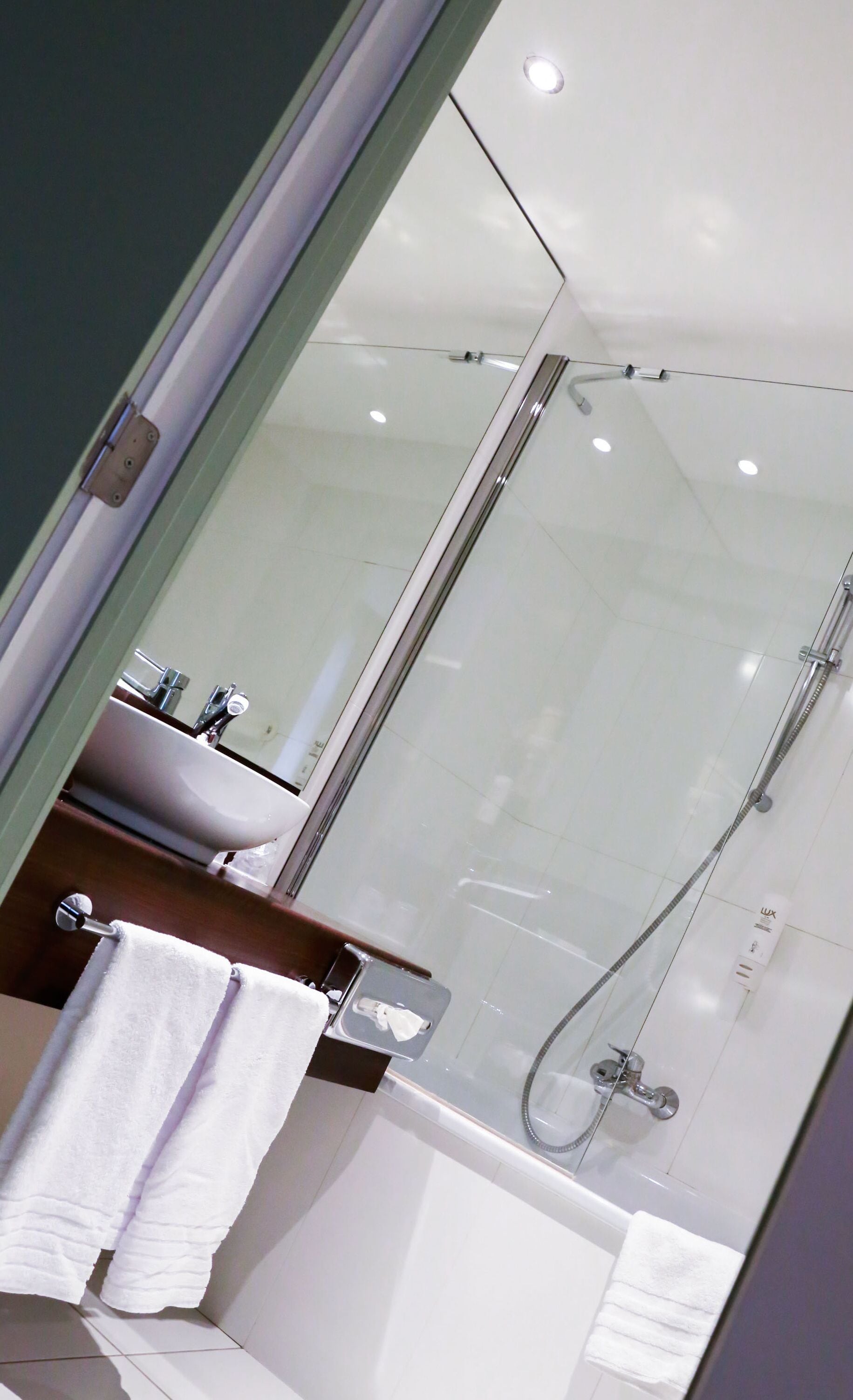 Une salle de bain moderne avec une douche à parois de verre, un lavabo et un miroir.