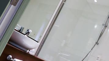 Une salle de bain moderne avec une douche à parois de verre, un lavabo et un miroir.