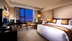 A hotel room with a large bed, a desk with a computer, a chair, and a TV. - GRAND NEW CENTURY HOTEL Binhai Tianjin (Tianjin)