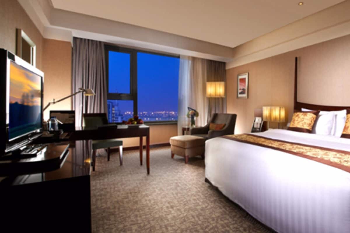 A hotel room with a large bed, a desk with a computer, a chair, and a TV.