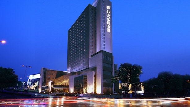 A modern hotel building with a prominent vertical structure and illuminated signage. - GRAND NEW CENTURY HOTEL Binhai Tianjin (Tianjin)
