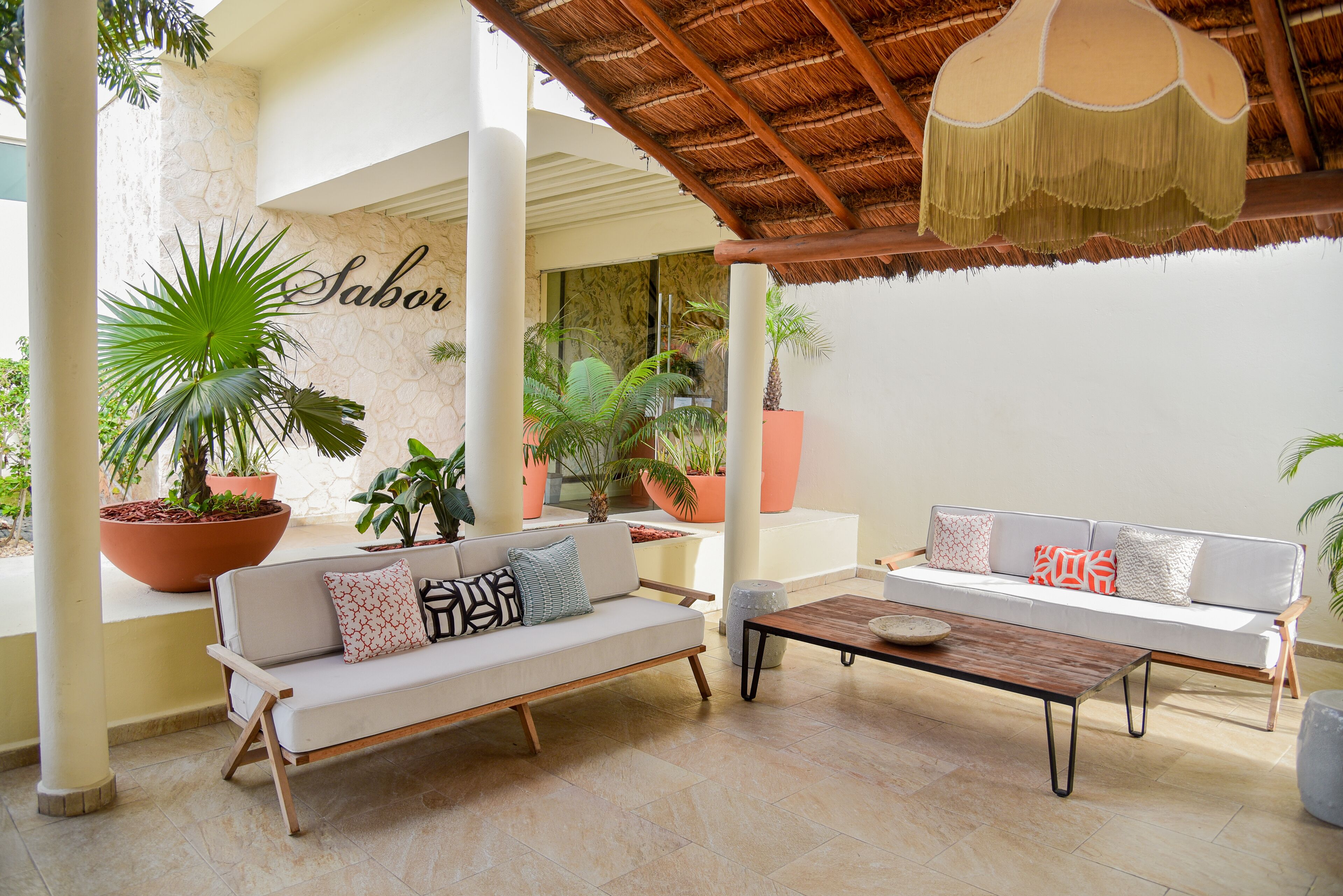 A modern outdoor seating area with two sofas, a coffee table, and potted plants.