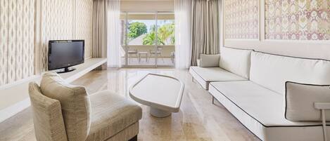A modern living room with a sofa, armchair, and a flat-screen TV on a stand.