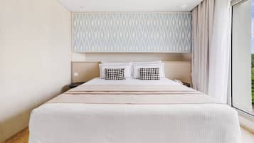 Quarto de hotel moderno com uma cama grande, cabeceira estampada e vista para o exterior.