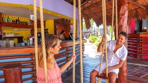 Una pareja en un columpio, con un bar y restaurante al fondo.