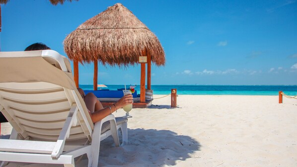En la playa, playa de arena blanca, camastros y sombrillas 