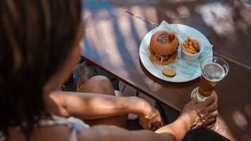 Una persona sentada a una mesa de madera con un plato de comida y una jarra de cerveza.