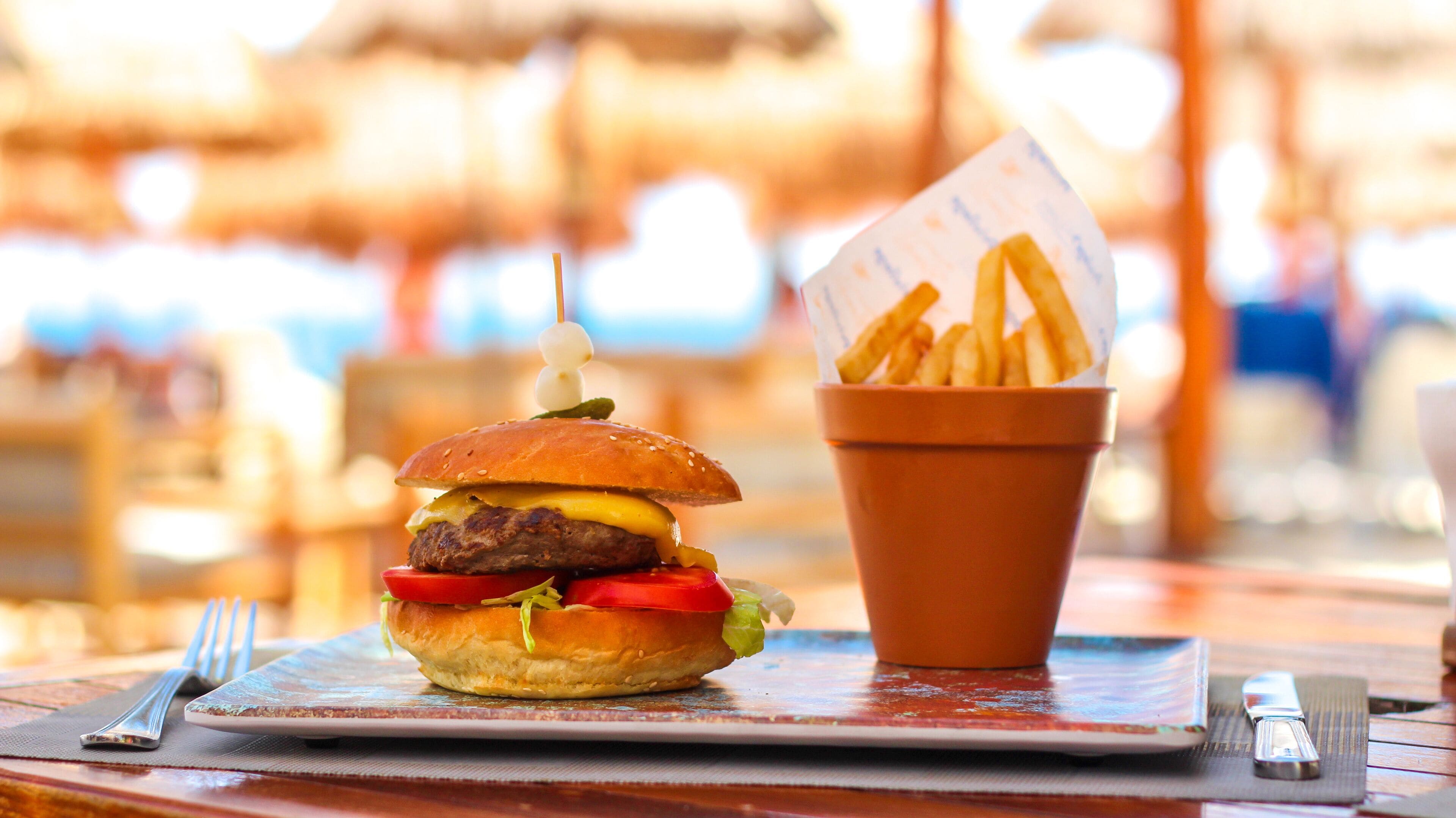 Un plato con una hamburguesa y papas fritas sobre una mesa de madera con un camino de mesa.
