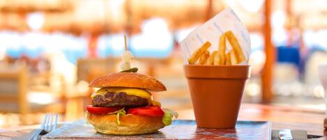 Un plato con una hamburguesa y papas fritas sobre una mesa de madera con un camino de mesa.
