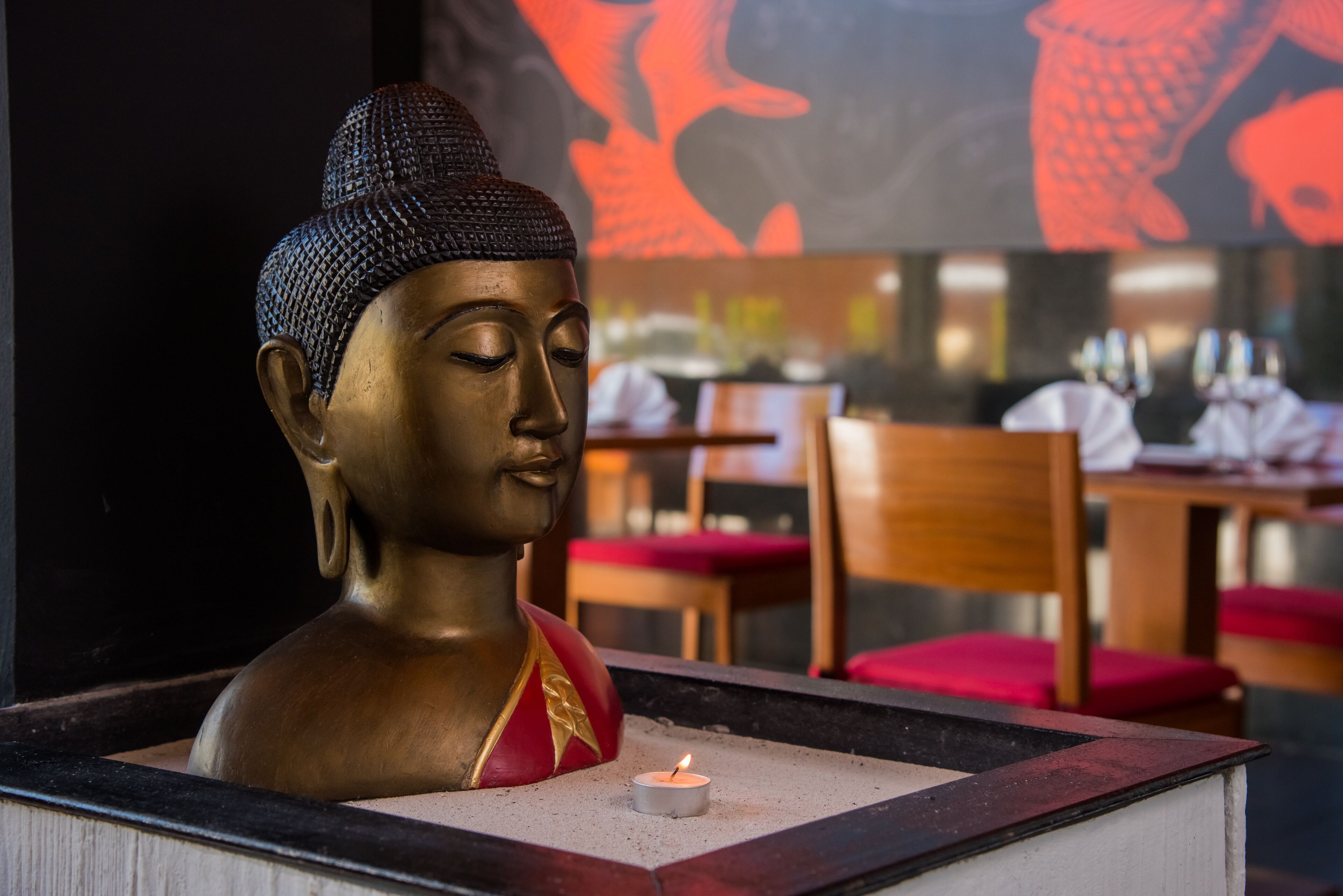 Eine Buddha-Statue mit einer brennenden Kerze davor.