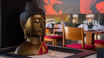 Eine Buddha-Statue mit einer brennenden Kerze davor.