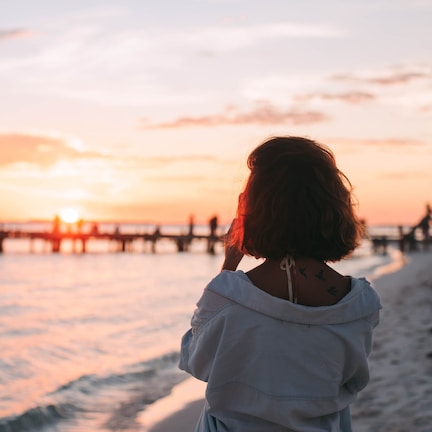 A person standing on a beach with a sunset in the background.