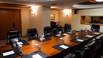 A conference room with a long table, black leather chairs, and water bottles.