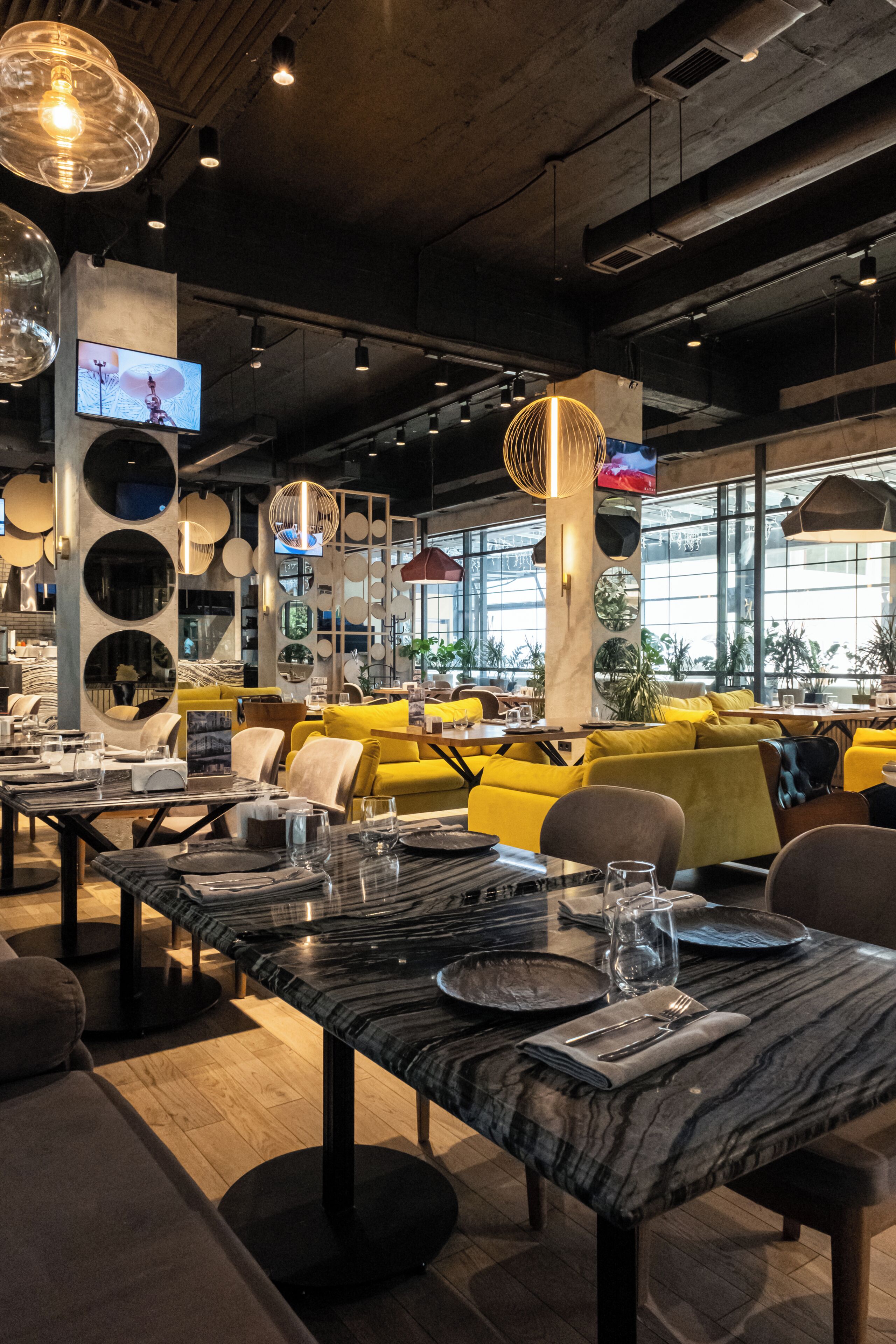 A restaurant with marble tables, yellow seating, and large windows.