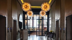 A hotel lobby with a grand piano, chandeliers, and a view through the glass doors. - Hotel Kazakhstan (Almaty)