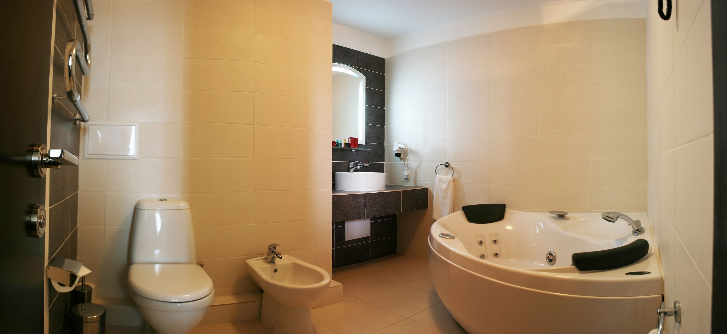 A modern bathroom with a toilet, bidet, bathtub, and a vanity with a mirror.