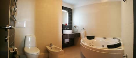 Une salle de bain moderne équipée d’un WC, d’un bidet, d’une baignoire et d’un meuble-lavabo avec un miroir.