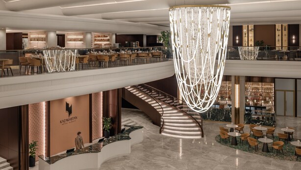 A hotel lobby with a reception desk, a staircase, and a dining area. - Hotel Kazakhstan (Almaty)