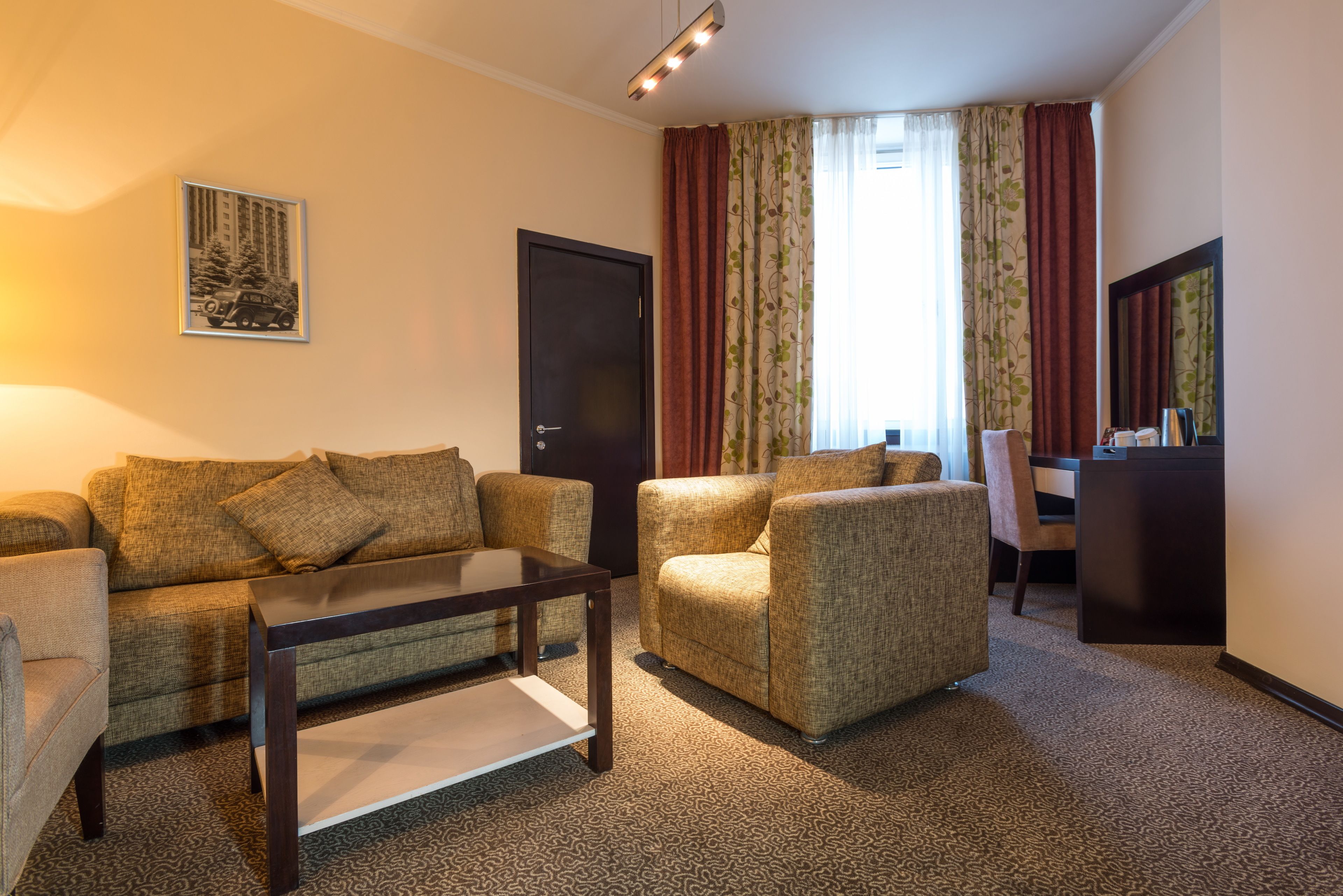 A furnished living room with a sofa, armchairs, a coffee table, a desk, and a chair.