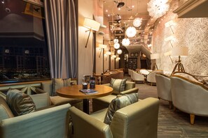 A well-lit lounge area with multiple seating options, including sofas and armchairs, arranged around a central table. - Hotel Kazakhstan (Almaty)