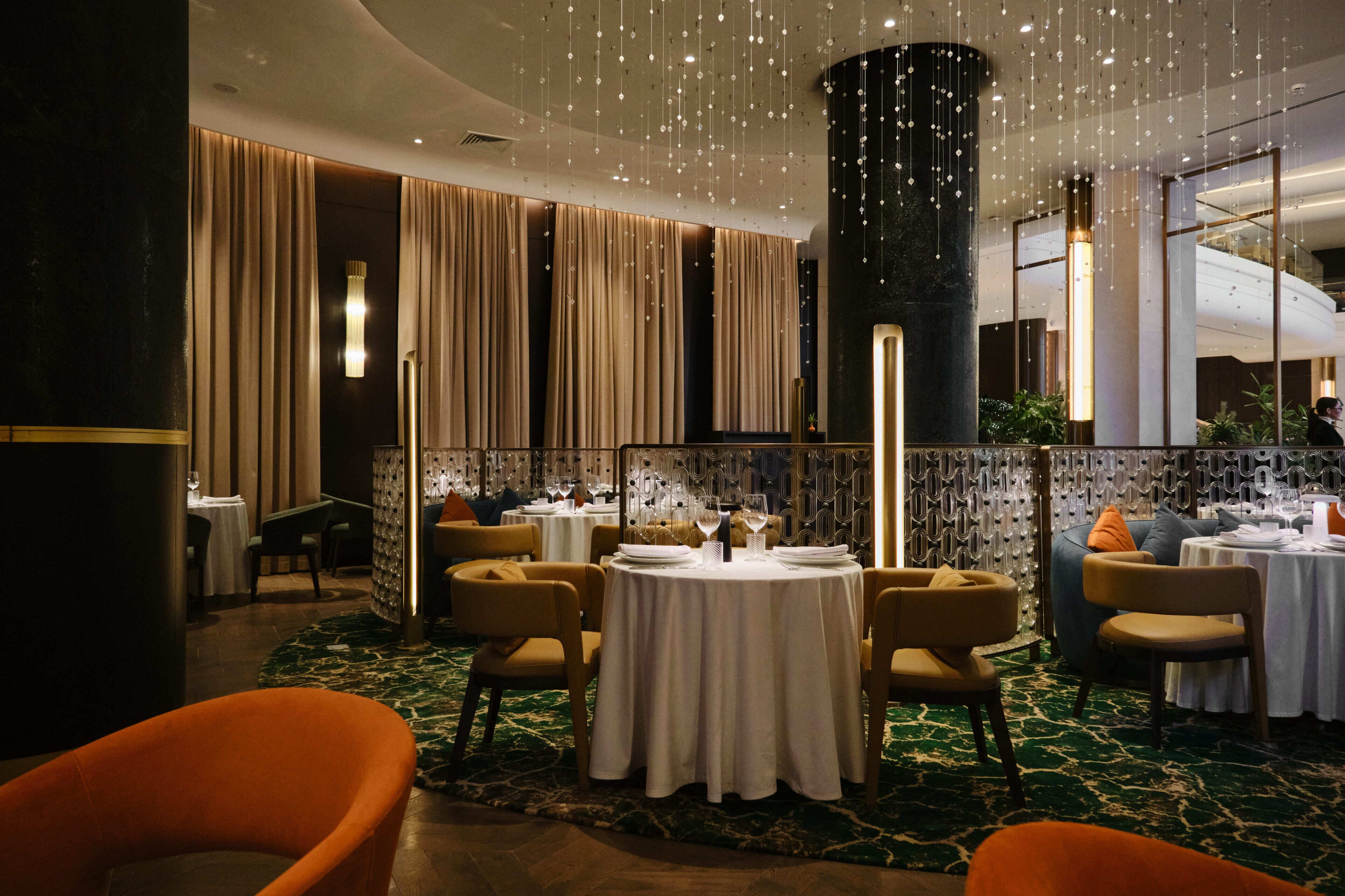 Ein Restaurant mit runden Tischen, Stühlen und hängenden Lampen.