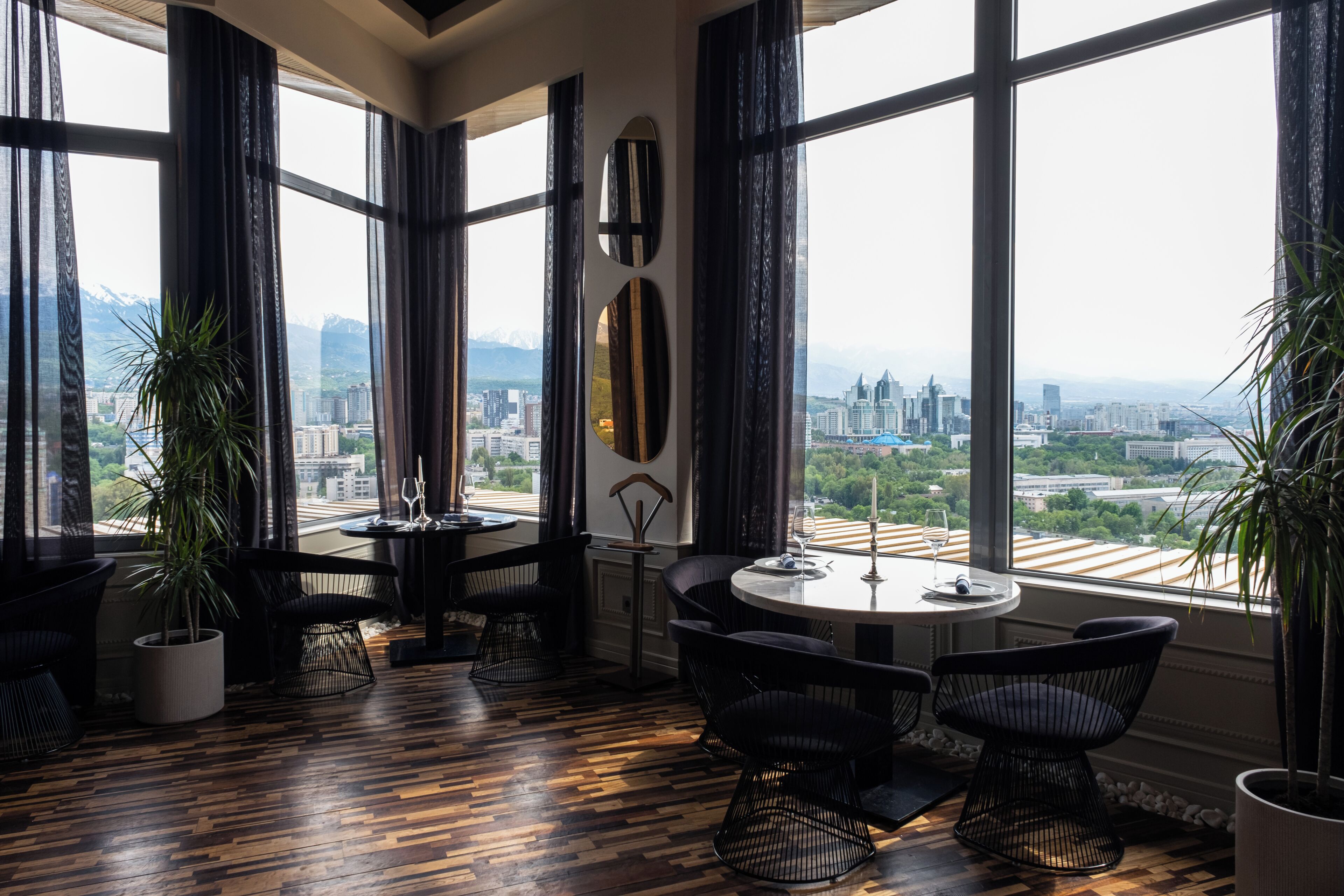 A room with large windows, a round table, and black chairs.
