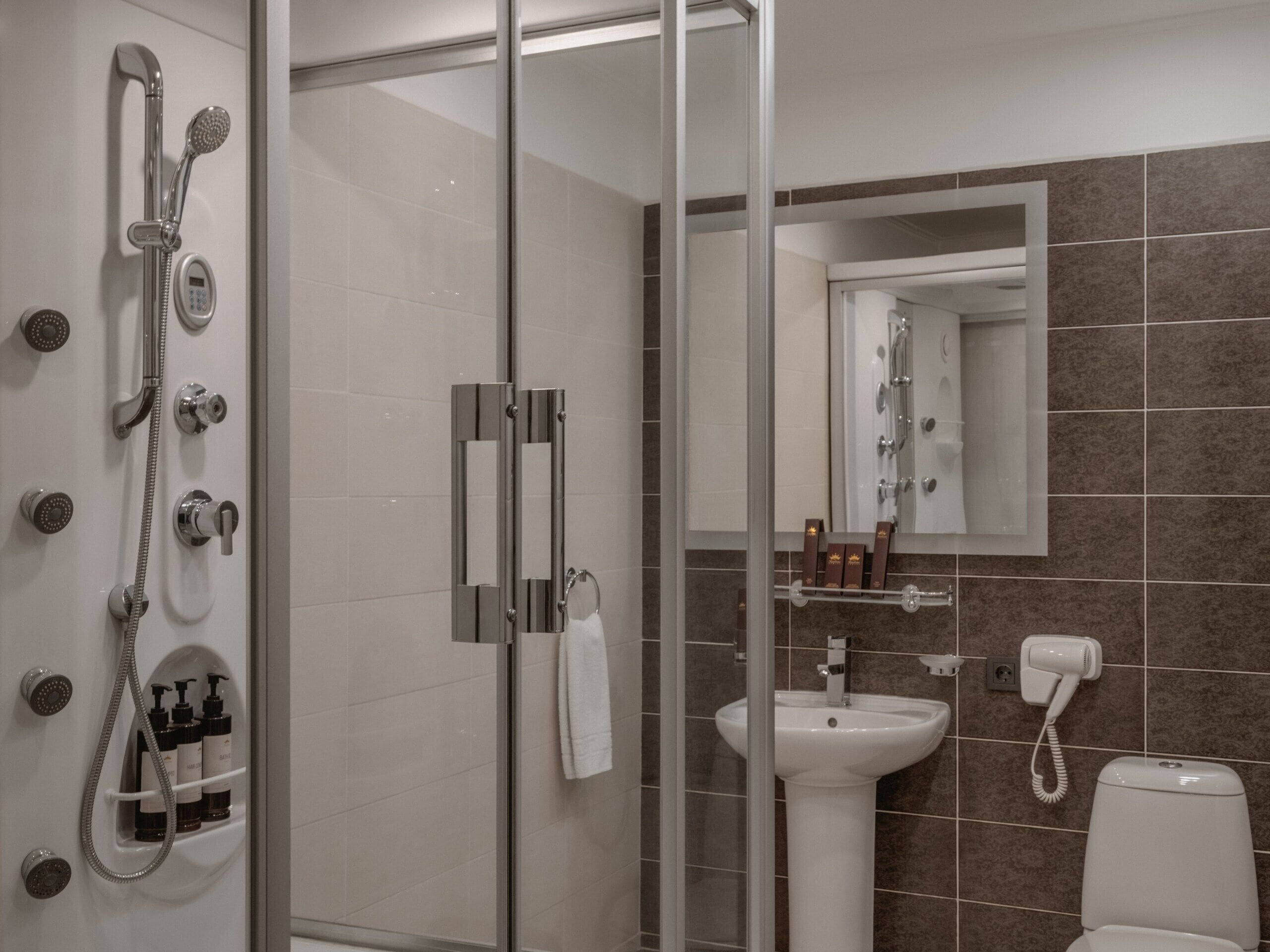 A modern bathroom with a glass shower enclosure, a white sink, and a mirror above the sink.
