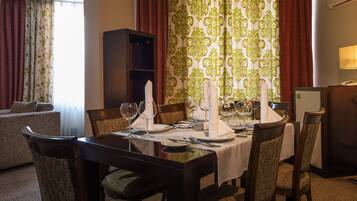 A dining area with a table set for six, surrounded by chairs, a sofa, and a bookshelf.