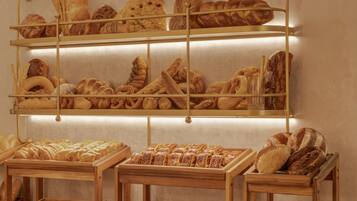 Een bakkerijetalage met verschillende broden en gebak op planken en toonbanken.