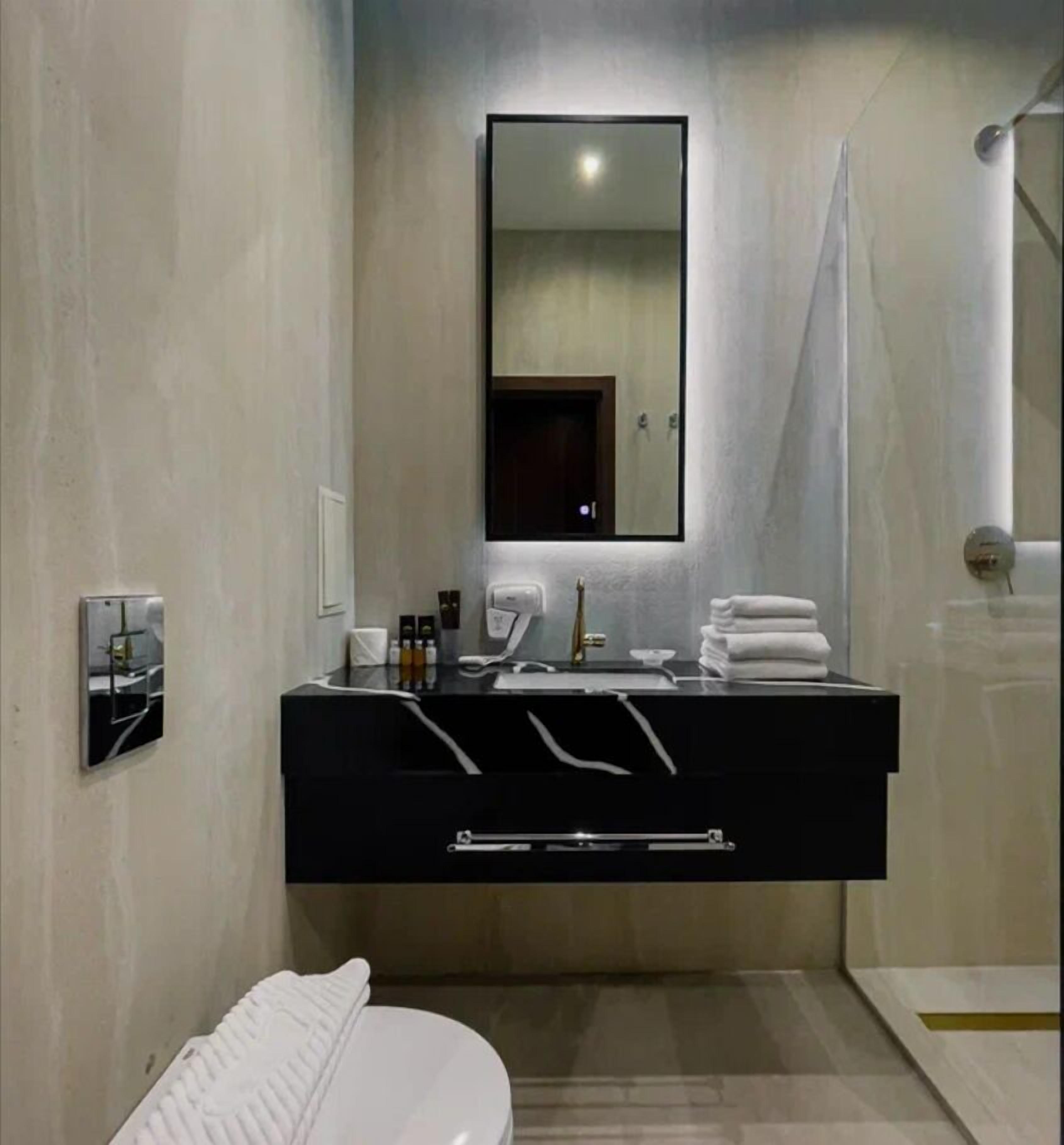A modern bathroom with a black vanity, a large mirror, and a white toilet.